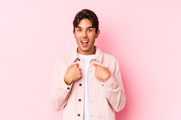 Jonge blanke man poseren in een roze achtergrond geïsoleerd verrast wijzend met vinger, breed glimlachend.