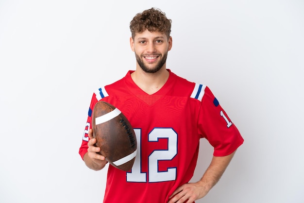 Jonge blanke man rugby spelen geïsoleerd op een witte achtergrond poseren met armen op heup en lachend