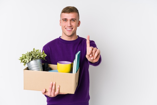 Jonge blanke man verhuizen naar een nieuw huis met nummer één met vinger.