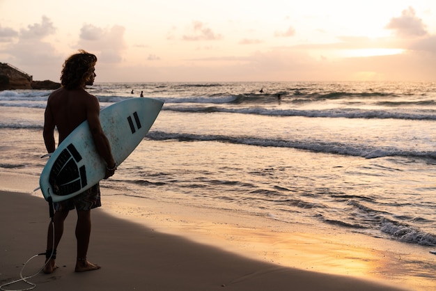 Jonge blanke man vroeg opstaan om te surfen bij zonsopgang