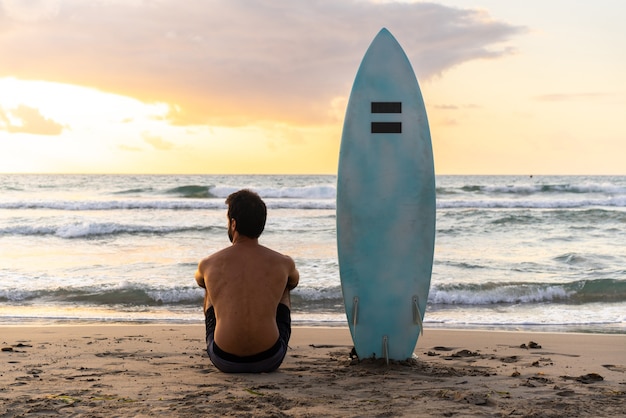 Jonge blanke man vroeg opstaan om te surfen bij zonsopgang