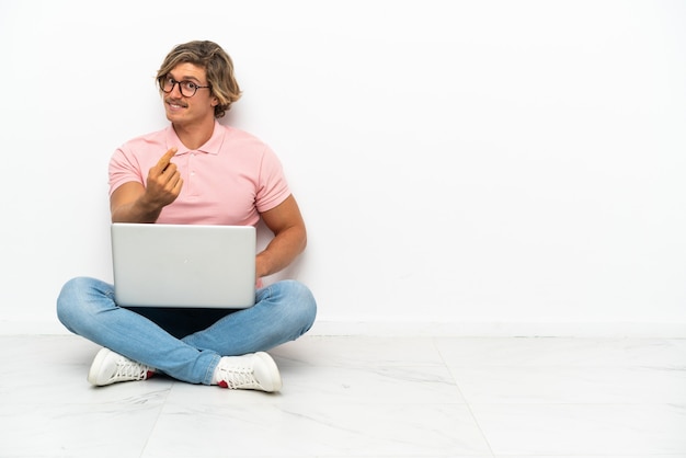 Jonge blanke man zittend op de vloer met zijn laptop geïsoleerd