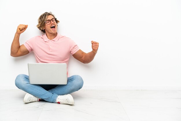 Jonge blanke man zittend op de vloer met zijn laptop geïsoleerd