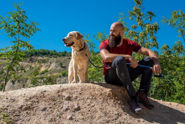 Jonge blanke mannelijke toerist die prachtige plekken verkent met zijn labrador retriever