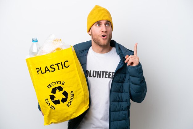 Jonge blanke met een zak vol plastic flessen om te recyclen, geïsoleerd op een witte achtergrond, denkend aan een idee met de vinger omhoog