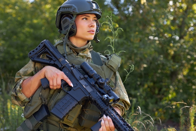 Jonge blanke militaire vrouw houdt een pistool in haar hand in de natuur