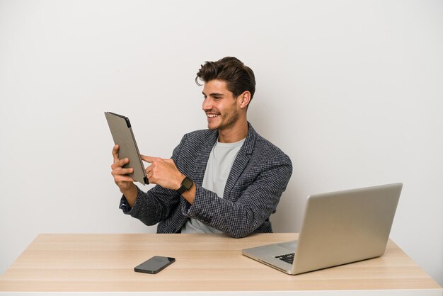 Jonge blanke ondernemer man aan het werk met laptop, mobiele telefoon en tablet