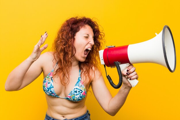 Jonge blanke roodharige vrouw met een megafoon