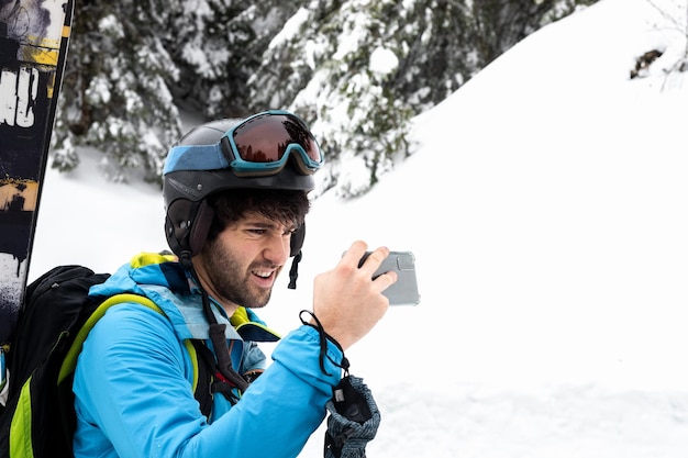 Jonge blanke skiër die een foto maakt op een besneeuwd bos.