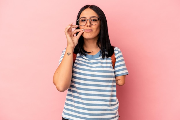 Jonge blanke student vrouw met één arm geïsoleerd op roze achtergrond met vingers op lippen houden een geheim.