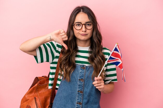 Jonge blanke studentenvrouw die Engels studeert geïsoleerd op een roze achtergrond met een afkeergebaar, duim omlaag. Onenigheid begrip.