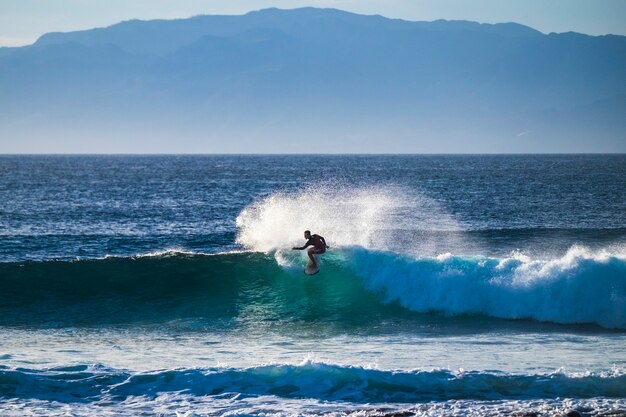 Jonge blanke tiener leert surfen op een grote deininggolf in de blauwe schone oceaan op een tropische plek tropical