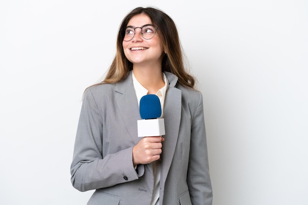 Jonge blanke tv-presentatorvrouw geïsoleerd op een witte achtergrond die een idee denkt terwijl ze omhoog kijkt