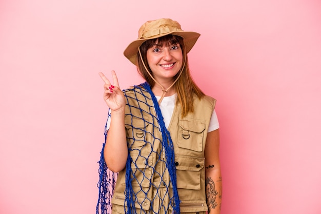 Jonge blanke vissersvrouw met net geïsoleerd op blauwe achtergrond vrolijk en zorgeloos met een vredessymbool met vingers.