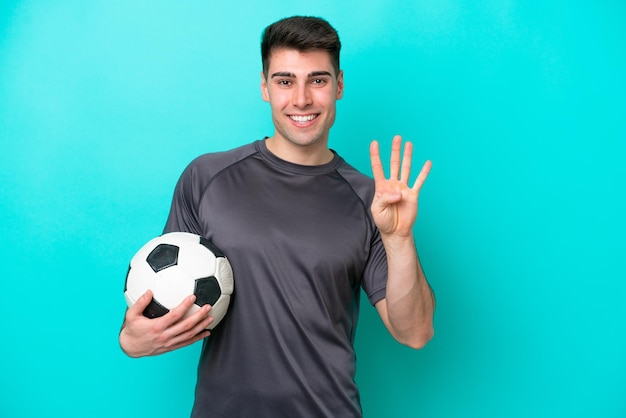 Jonge blanke voetballer man geïsoleerd op blauwe achtergrond gelukkig en tellen vier met vingers