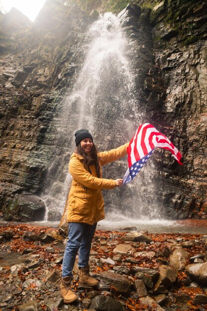 Jonge blanke volwassen vrouw met usa vlag voor waterval