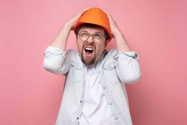 Jonge blanke voorman met oranje helm is bang voor zijn veiligheid