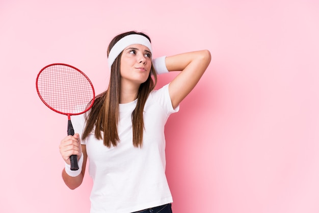 Jonge blanke vrouw badminton spelen geïsoleerd achterkant van het hoofd aanraken, denken en een keuze maken.