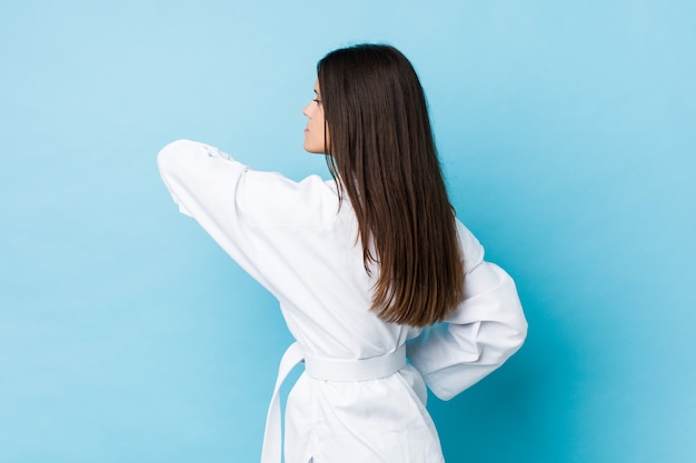 Jonge blanke vrouw beoefenen van karate geïsoleerd op een blauwe muur