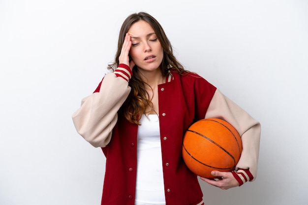 Jonge blanke vrouw die basketbal speelt geïsoleerd op een witte achtergrond met hoofdpijn