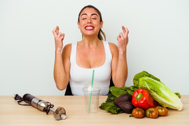 Jonge blanke vrouw die een gezonde smoothie met groenten bereidt