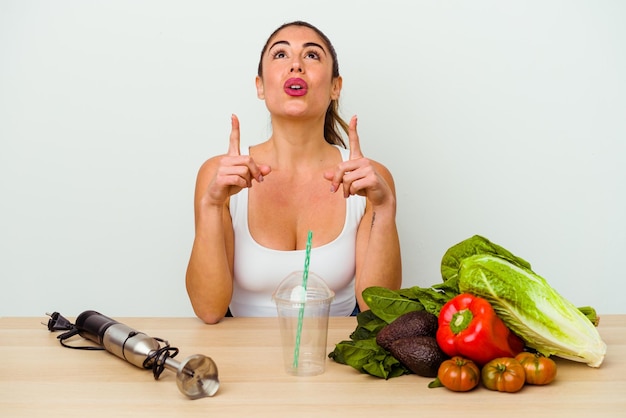 Jonge blanke vrouw die een gezonde smoothie met groenten bereidt