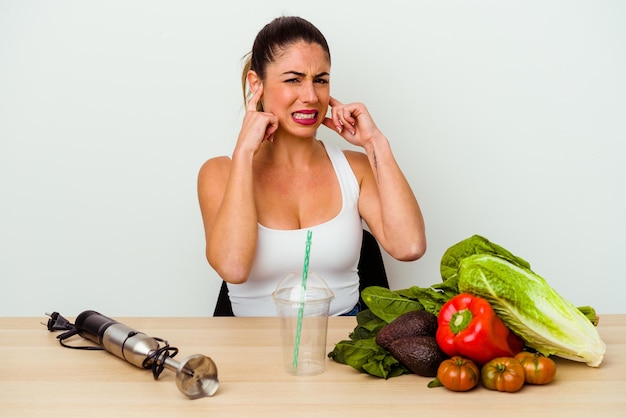 Jonge blanke vrouw die een gezonde smoothie met groenten bereidt