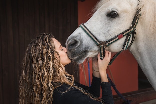 Jonge blanke vrouw die een paard kust a