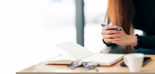 Jonge blanke vrouw die een pen vasthoudt die aan een bureau zit, denkt en plant voor een nieuw zakelijk project. Bijgesneden afbeelding met kopie ruimte.