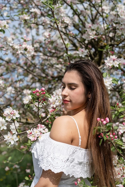 Jonge blanke vrouw die geniet van de bloei van een appelboom