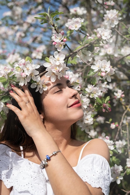 Jonge blanke vrouw die geniet van de bloei van een appelboom