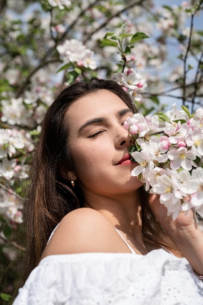 Jonge blanke vrouw die geniet van de bloei van een appelboom