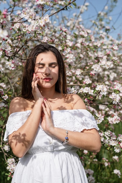 Jonge blanke vrouw die geniet van de bloei van een appelboom