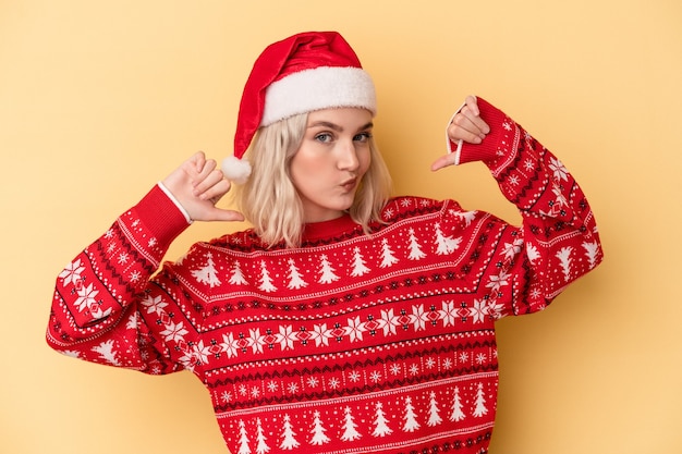 Jonge blanke vrouw die Kerstmis viert geïsoleerd op gele achtergrond voelt zich trots en zelfverzekerd, voorbeeld om te volgen.