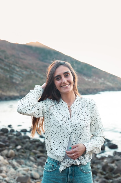 Jonge blanke vrouw die lacht in een wit overhemd op het strand