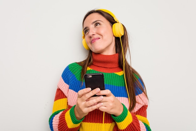 Jonge blanke vrouw die naar muziek luistert met een koptelefoon die haar mobiele telefoon aanraakt