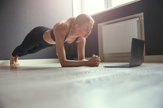 Jonge blanke vrouw die ochtendsport oefeningen thuis doet