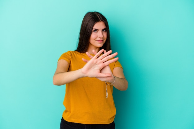 Jonge blanke vrouw die op blauwe achtergrond wordt geïsoleerd die een ontkenningsgebaar doet