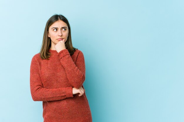 Jonge blanke vrouw die opzij kijkt met een twijfelachtige en sceptische uitdrukking.