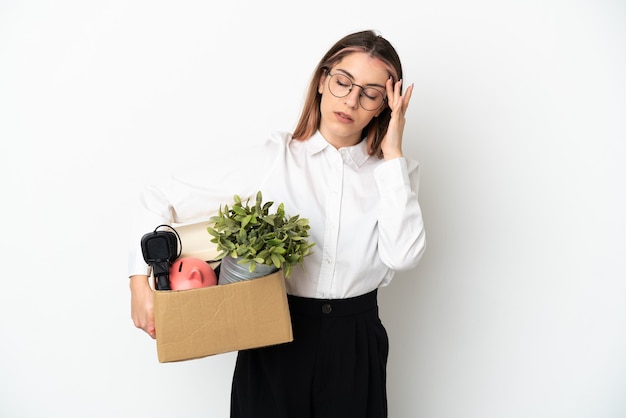 Jonge blanke vrouw die zich in een nieuw huis onder dozen beweegt die op een witte muur met hoofdpijn worden geïsoleerd