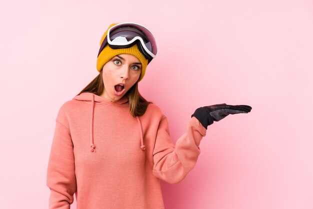 Jonge blanke vrouw draagt een ski kleding geïsoleerd onder de indruk houden kopie ruimte op palm.