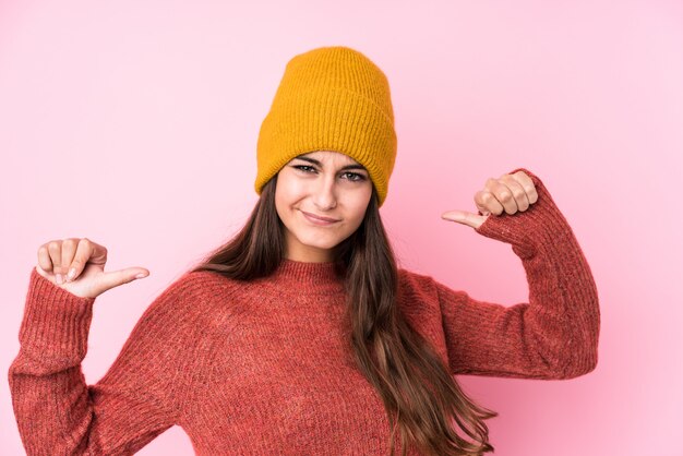 Jonge blanke vrouw draagt een wollen muts voelt zich trots en zelfverzekerd, voorbeeld te volgen.