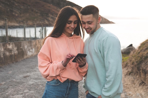 Jonge blanke vrouw en man geleid door een smartphone aan de kust