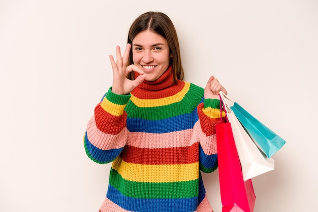 Jonge blanke vrouw gaat winkelen geïsoleerd op een witte achtergrond, vrolijk en zelfverzekerd met een goed gebaar