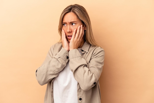 Jonge blanke vrouw geïsoleerd op beige achtergrond bang en bang.