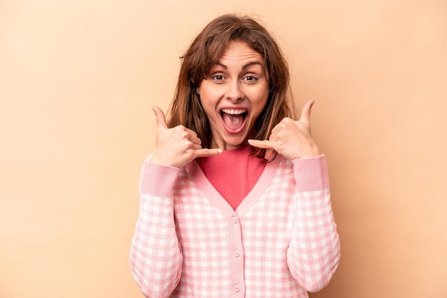 Jonge blanke vrouw geïsoleerd op beige achtergrond met een mobiel telefoongesprek gebaar met vingers