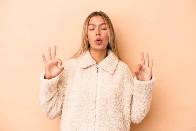 Jonge blanke vrouw geïsoleerd op beige achtergrond ontspant na een zware werkdag, ze voert yoga uit.