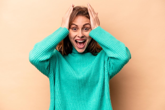 Jonge blanke vrouw geïsoleerd op beige achtergrond schreeuwend erg opgewonden gepassioneerd tevreden met iets