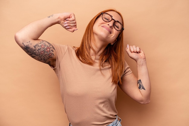 Jonge blanke vrouw geïsoleerd op beige achtergrond strekkende armen, ontspannen positie.