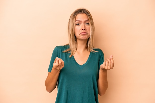 Jonge blanke vrouw geïsoleerd op beige achtergrond waaruit blijkt dat ze geen geld heeft.